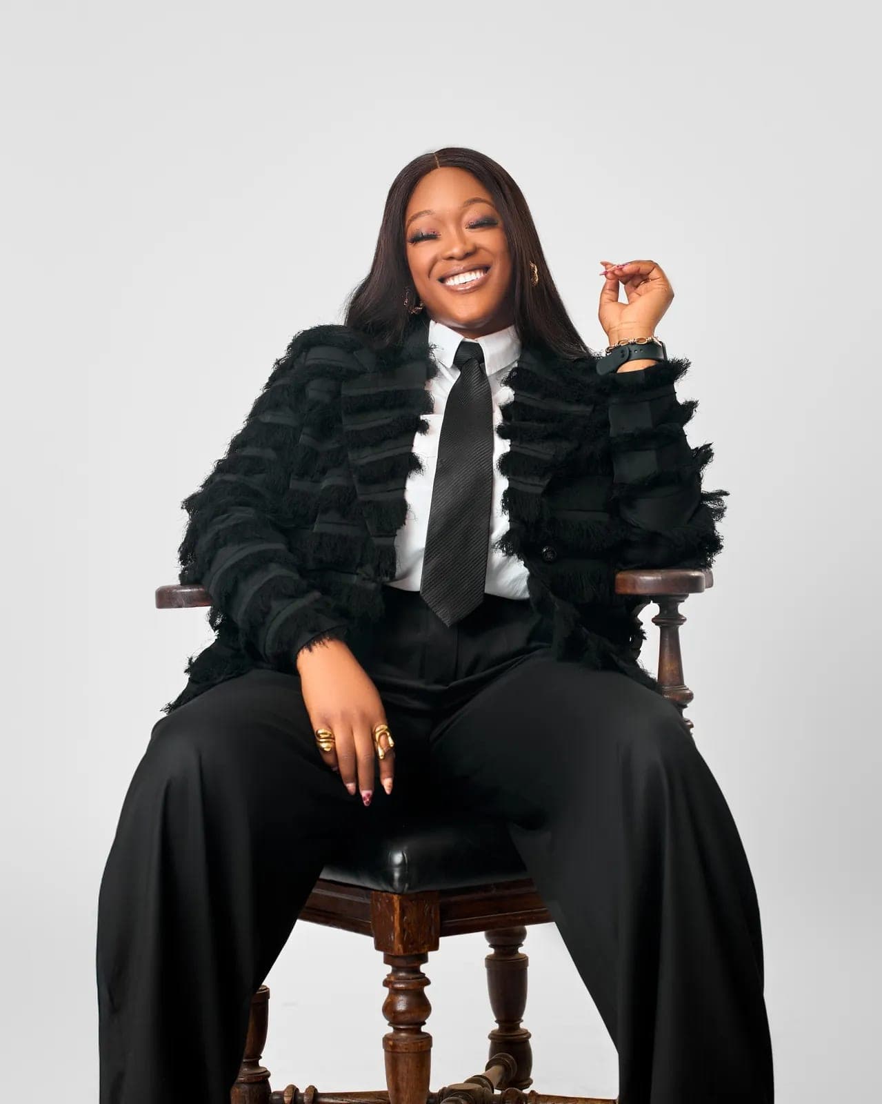 Studio portrait of Petra Odubayo seated in a black suit and tie